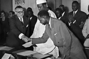 Mamadou Dia, vice-président du Mali (à droite) serre la main de Louis Jacquinot, ministre d’Etat français, sous le regard de Modibo Keita, chef d’Etat malien à Dakar, le 20 juin 1960, lors de la proclamation de l’indépendance de la Fédération du Mali (Sénégal et Soudan).